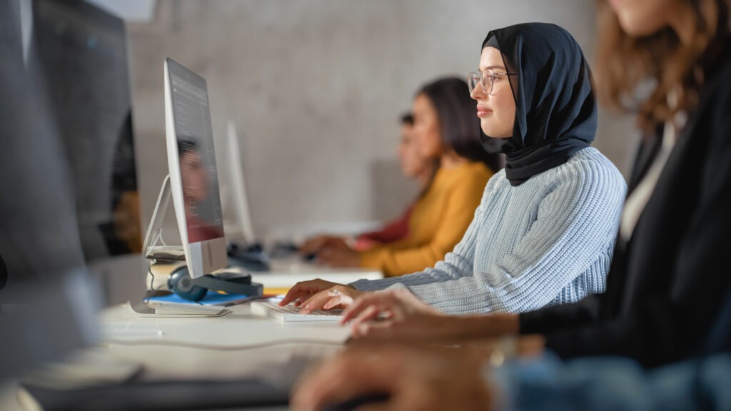 happy female muslim student wearing hijab studying modern university with diverse multiethnic classmates students successfully learn computer science writing software code scaled